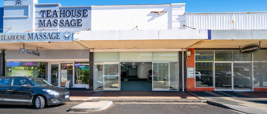 An empty shopfront in the Bunbury CBD, glass frontage and bare interior, between a massage business and a marine dealer.